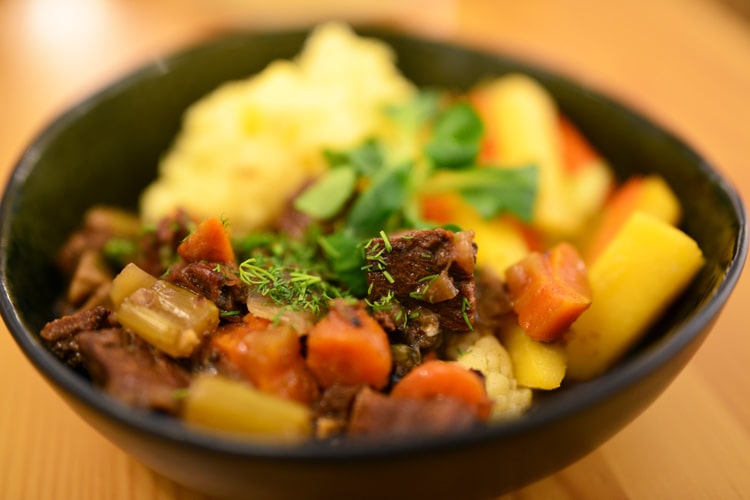 Mясо лося с грибами тушеное в темном пиве, с картофельным пюре и местными корнеплодами