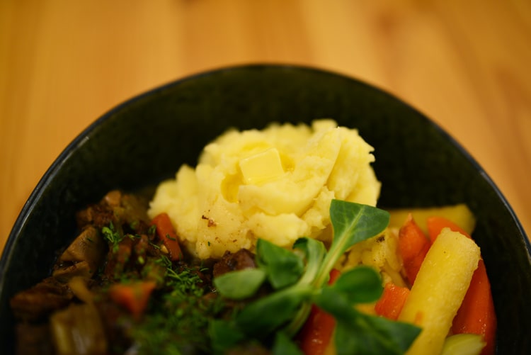 Mясо лося с грибами тушеное в темном пиве, с картофельным пюре и местными корнеплодами